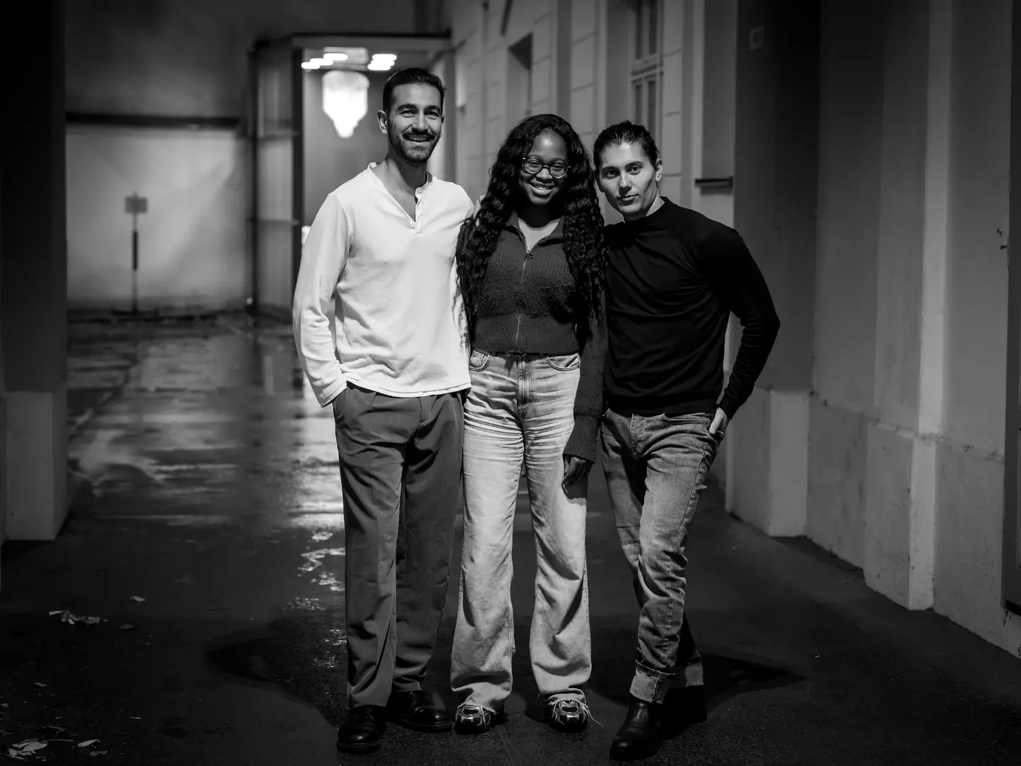 Three friends standing together in a city archway at night